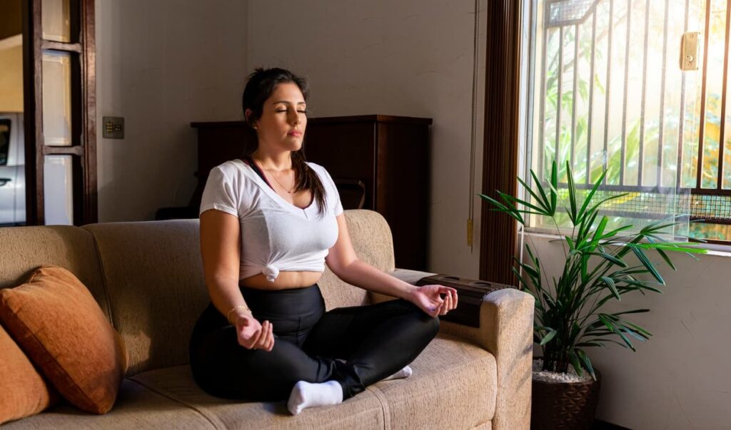Meditação. Mulher medita no sofá
