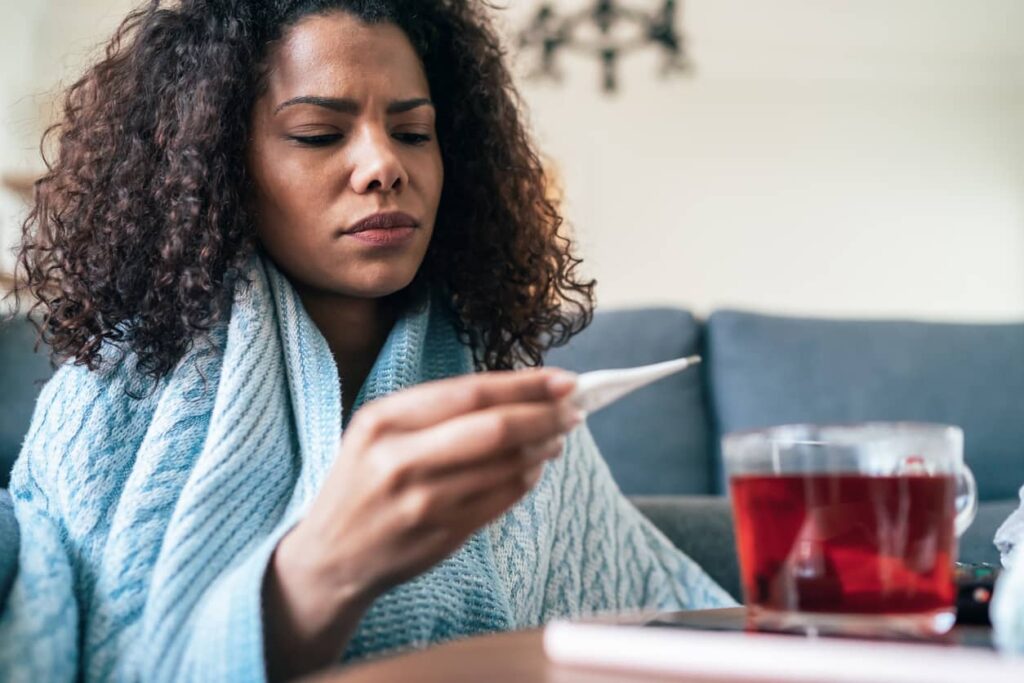 Gripe ou resfriado. Mulher afere temperatura