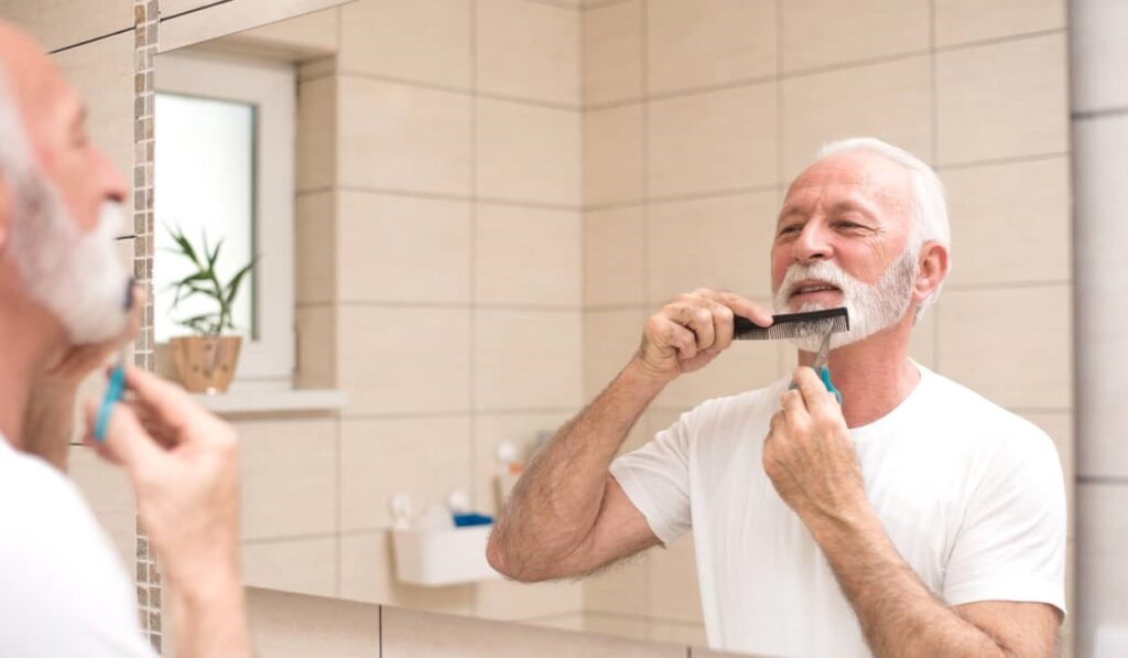 Homem apara a barba com tesoura